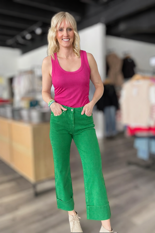 Woman wearing a pink tank top and green pants in an indoor setting